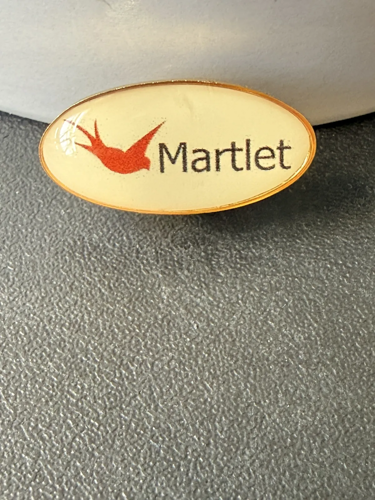 Oval Martlet logo printed pin badge in gold