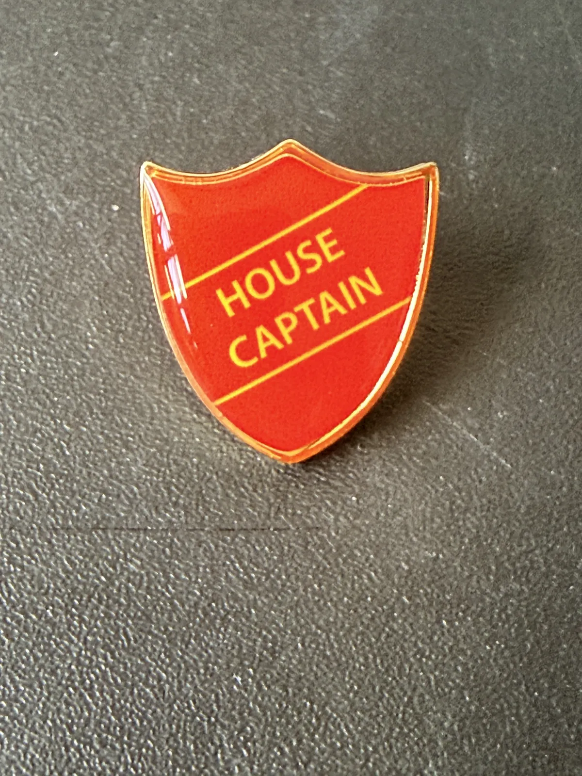 Red House Captain shield-shaped pin badge